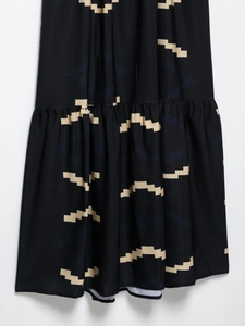Detail of geometric print fabric with ruffled tiered layers on a black summer dress