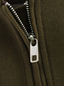 Detailed close-up of a silver metal zipper on olive green ribbed knit vest fabric