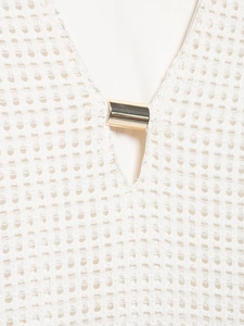 Detail of V-neckline with gold metallic trim on off-white crochet knit midi dress