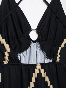 Close-up of black halter dress with deep V-neck, metal ring detail, and geometric prints