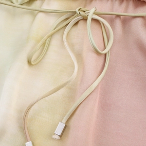 Détail de robe midi tie-dye avec dégradé pastel doux et embouts de cordon en métal argent