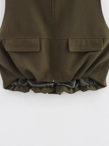 Detail of olive green vest showing symmetrical flap pockets and zippered elastic hemline