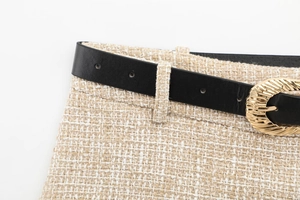 Detail view of tweed shorts with a black leather belt and textured gold buckle