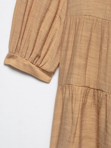 Detail of light khaki textured crepe dress showing puff sleeve cuffs and stitching design