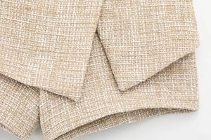 Close-up of premium beige tweed fabric texture showing intricate woven details