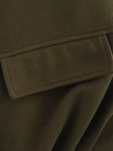 Detail showing the textured wool fabric and flap pocket of the olive green vest