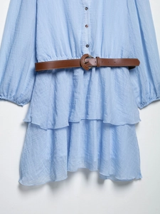 Détail d'une robe bleu clair avec volants étagés et ceinture marron en similicuir