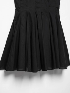 Détail des plis verticaux denses sur une robe courte noire avec silhouette trapèze chic