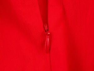 Détail d'une robe midi rouge montrant une fermeture éclair invisible et la texture du tissu