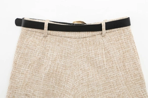Detailed view of beige tweed fabric texture with a slim black leather belt and gold buckle