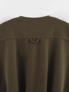 Detail of dark olive green sleeveless vest featuring a functional D-ring loop on the back