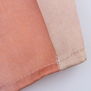 Détail des coutures du tissu satiné et de la finition du bord de la robe midi