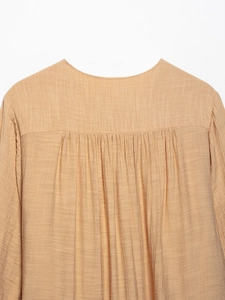 Detail view of apricot pleated fabric texture and smocked back design on women dress