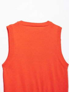 Detailaufnahme der orangefarbenen Strickweste mit Rippenstrick am Hals und Ärmel