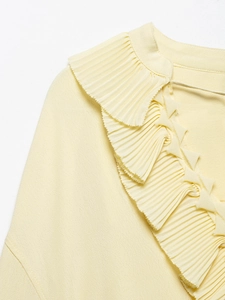 Detail of elegant V-neckline with pleated ruffles on light yellow chiffon shirt
