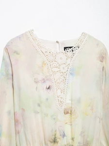 Detailed close-up of V-neck crochet lace trim and floral chiffon fabric on the summer dress