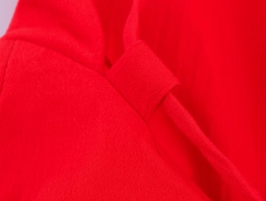 Détail macro du passant de ceinture en tissu rouge et des coutures sur la robe midi