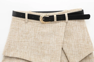 Close-up of beige tweed skirt with a slim black leather belt and gold embossed buckle