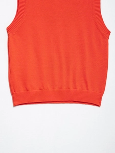 Detailansicht der leuchtend orangefarbenen Strickweste mit feiner Rippenstruktur am Saum