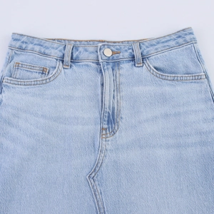 Gros plan d'une jupe en jean bleu clair avec boutons argentés et taille haute détaillée
