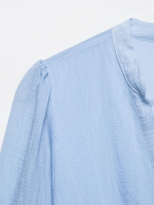 Détail de la robe en mousseline bleu clair avec manches bouffantes et tissu texturé