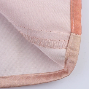 Détail des bords en tissu rose avec bordure en satin doré champagne et coutures précises