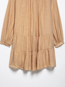 Close-up of tiered crinkle fabric in beige showing pleated texture and refined stitching