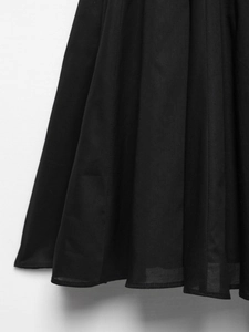 Détail de l'ourlet de la robe plissée noire montrant les coutures fines et la texture du tissu