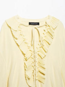 Detail of V-neck ruffled lace trim and tie-up drawstring on light yellow blouse