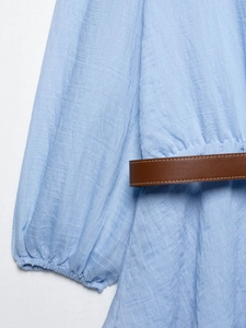 Gros plan détaillé du tissu en mousseline plissée bleu clair avec ceinture en cuir brun
