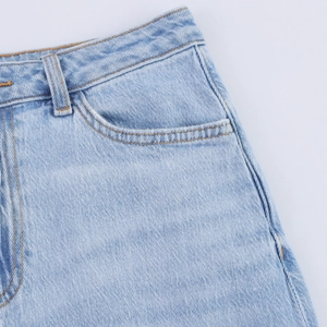 Détail d'une jupe en jean délavé avec coutures rousses et design de poche classique
