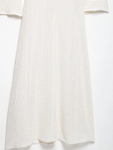 Detail shot of off-white midi dress featuring textured waffle knit fabric and flared hemline