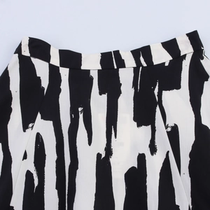Detailed close-up of the high-waist band and abstract black ink print on white midi skirt
