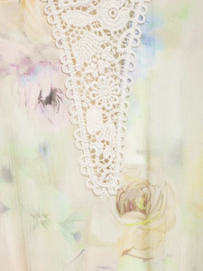 Macro detail of floral print dress with intricate white crochet lace trim on light fabric