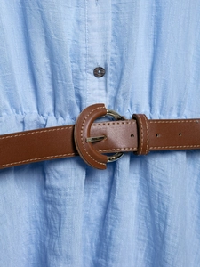Détail du tissu texturé bleu ciel avec une ceinture en similicuir marron et boucle dorée