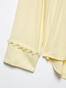 Detailed close-up of light yellow shirt sleeve featuring unique 3D floral lace edge