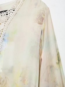 Detailed view of the lace crochet neckline and floral print on white chiffon fabric
