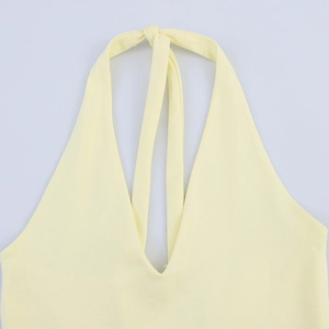 Detail of light yellow halter neck dress featuring deep V-neck and soft knit texture