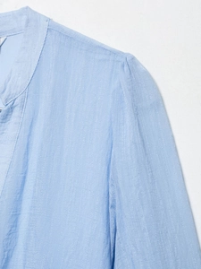 Détail de la robe en mousseline bleu clair montrant les plis aux épaules et la texture