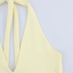 Detailed view of the halter neck tie and deep V-neckline on a soft pale yellow knit dress