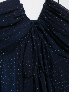 Detail of navy blue polka dot dress featuring V-neckline and delicate pleated tie front