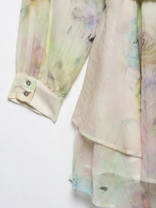 Close-up of chiffon floral dress sleeve with delicate buttons and sheer fabric details