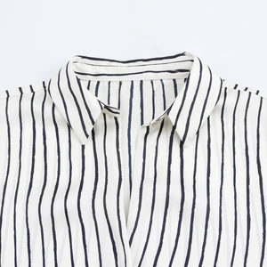 Detail view of the classic lapel and black vertical stripes on this white satin shirt