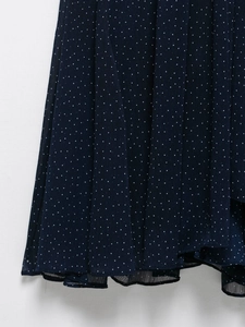Detail of dark blue polka dot chiffon dress showing pleated texture and semi-transparent hem