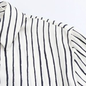 Detail of white shirt with black vertical stripes showing collar and pleated shoulder seams