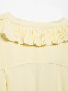 Detail of cream chiffon fabric showing ruffled V-neckline and fine pleated texture