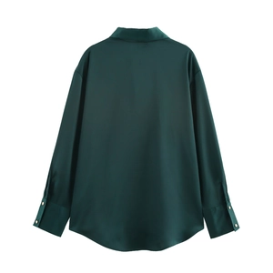Detail of dark green satin shirt featuring wide cuffs and elegant gold button accents
