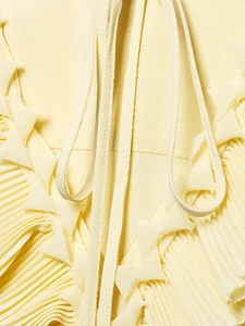 Detail of light yellow pleated chiffon fabric with ruffled edges and delicate tie straps