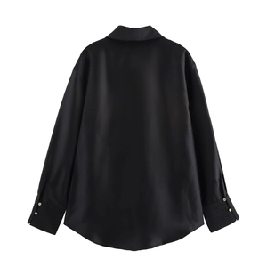 Detail view of black satin shirt back with long sleeves and elegant gold cuff buttons