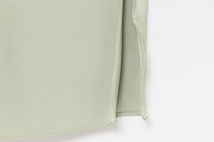 Detailed close-up of side slit and high-quality stitching on light green satin dress